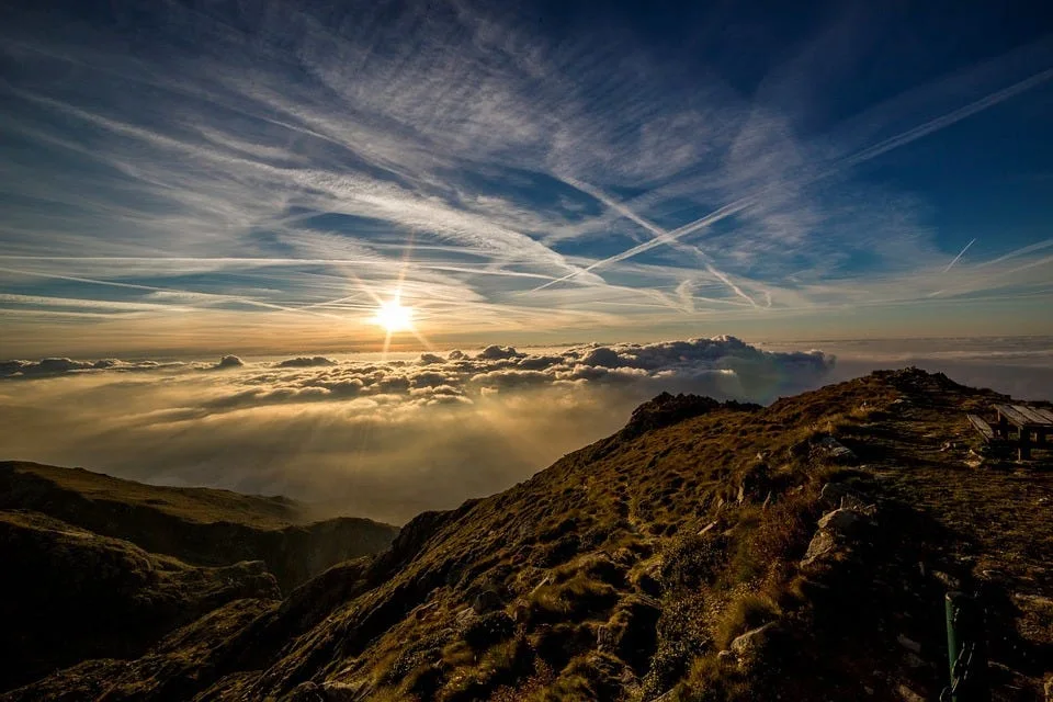 Sunrise above a mountain summit under streaked clouds